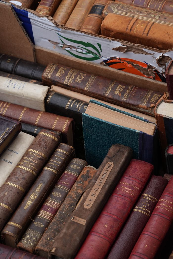 Vintage hardcover books in a worn cardboard box. Perfect for antique or literature enthusiasts.